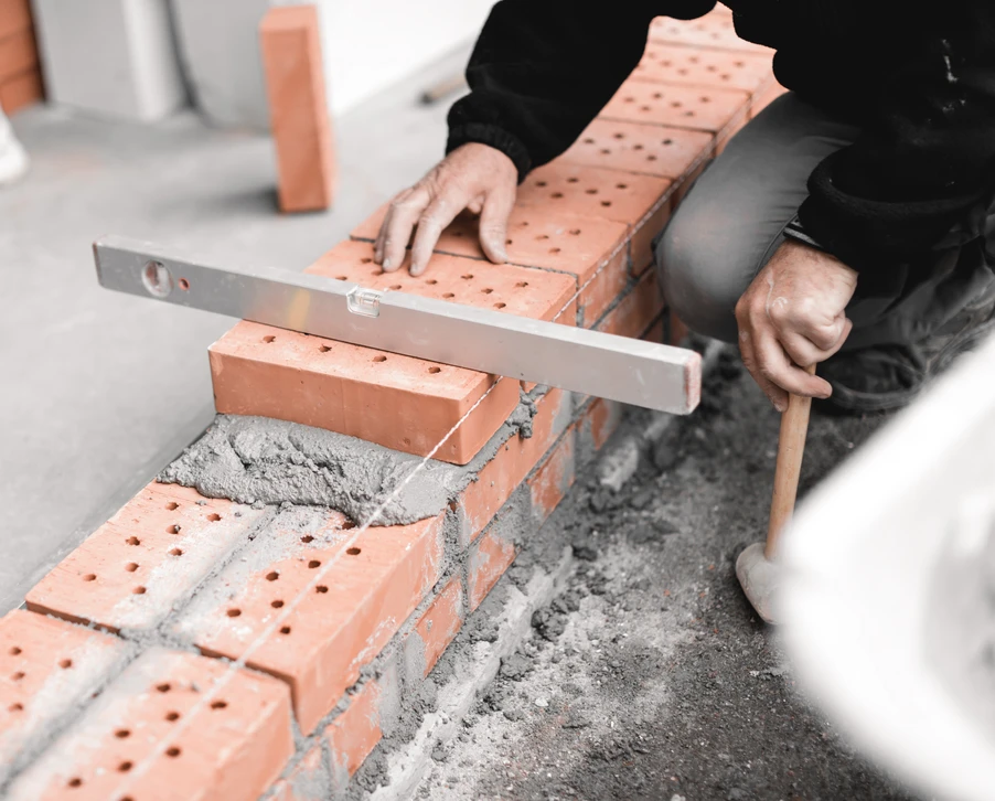 main-d'oeuvre vérifiant le niveau de surface du mur de briques avec le niveau d'esprit