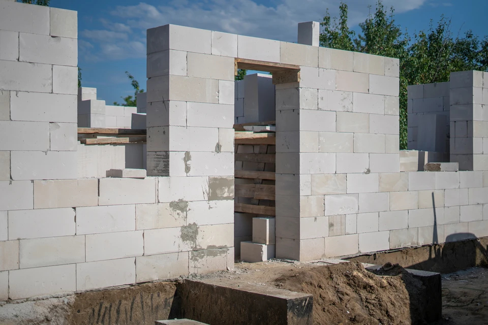 Homme d'âge mûr souriant, bras croisés, debout devant camionnette blanche stationnée