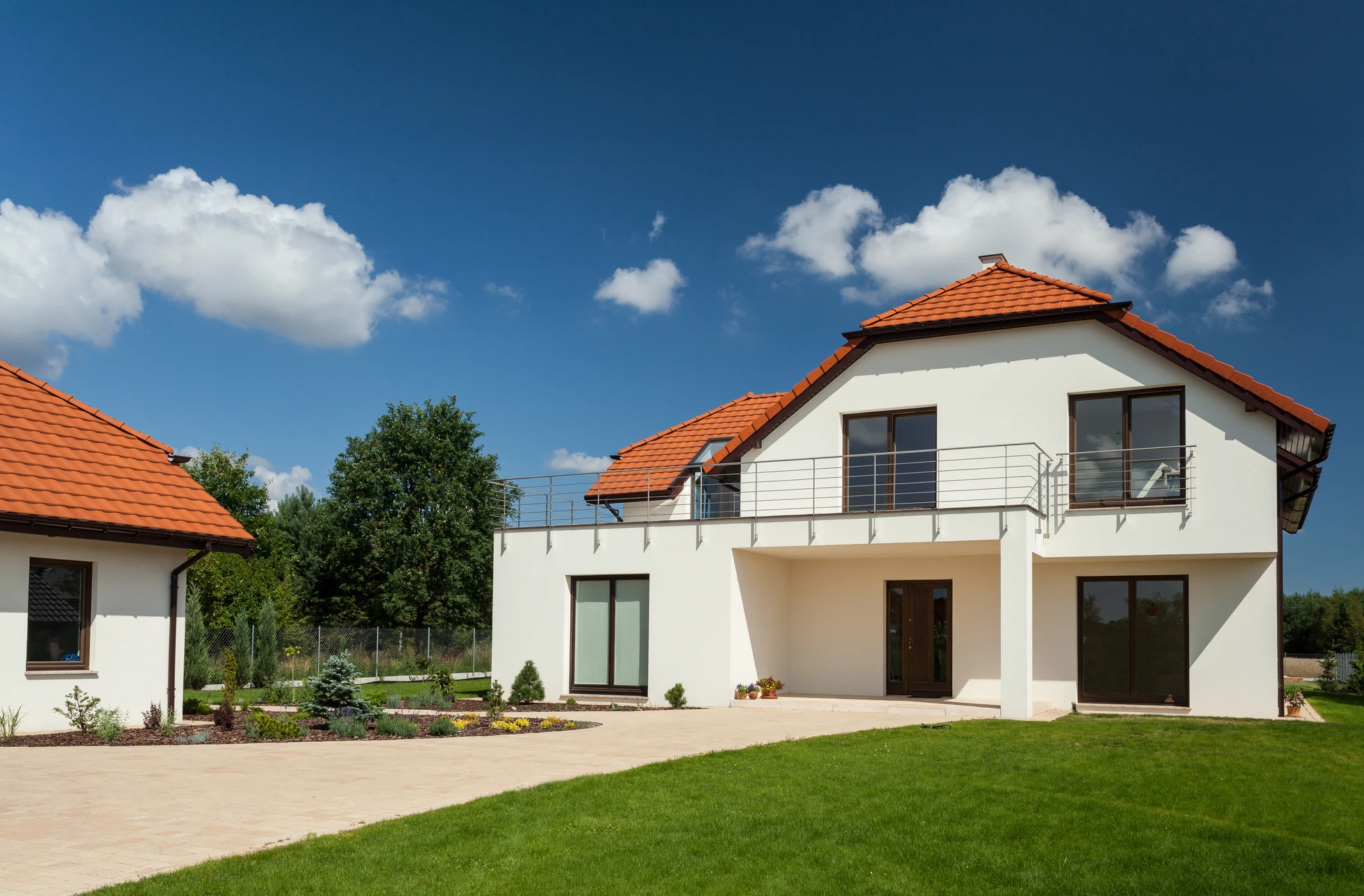Façade de maison traditionnelle française aux murs blancs avec volets bleus ouverts, porte-fenêtre centrale et fenêtres à l'étage